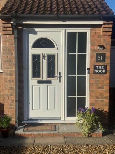 a white door on a house with a sign on it at The Nook in Holbeach
