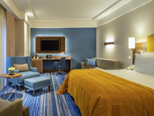 a hotel room with a bed and a desk and a tv at Mövenpick Hotel Istanbul Asia Airport in Istanbul