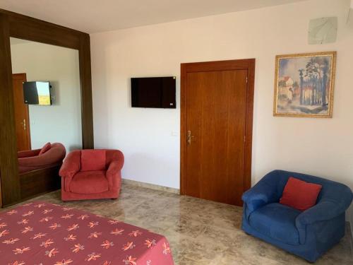 a room with two chairs and a bed and a television at I 4 Venti in Melendugno