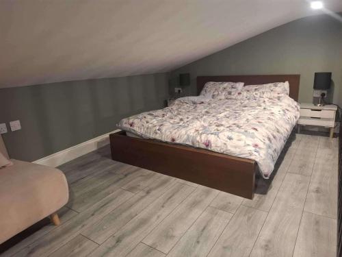 een slaapkamer met een bed en een houten vloer bij Studio - Sleeps 4 - Garden - Parking - Wifi in Blessington
