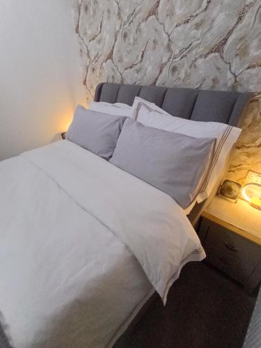 a bed with white sheets and pillows next to a stone wall at Bavelle Bilston Urban Village in Bilston