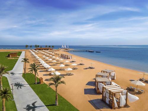 Una playa con sillas y sombrillas y el océano. en Rixos Premium Magawish Suites and Villas- Ultra All-Inclusive, en Hurghada