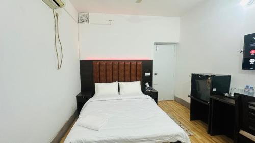 a small room with a bed and a desk at Chittagong Apartment Service Guest House in Dhaka