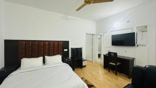 a bedroom with a large bed and a flat screen tv at Chittagong Apartment Service Guest House in Dhaka