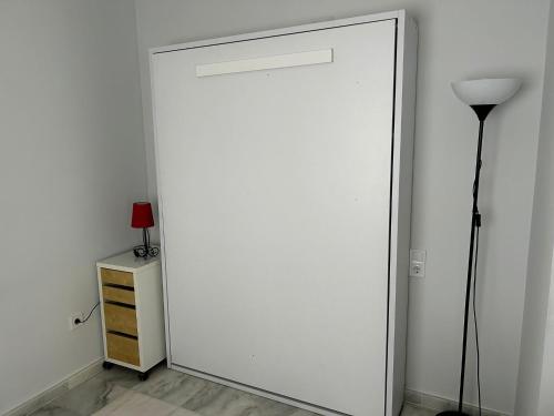 a white door in a room with a lamp and a dresser at Atico playa de Rota in Rota