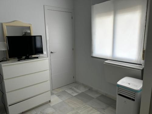 a white room with a television and a window at Atico playa de Rota in Rota