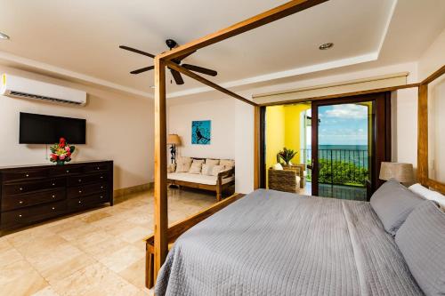 a bedroom with a bed and a television and a couch at Beachfront Oceanview Private Jacuzzi & Full Ktcn in Tamarindo