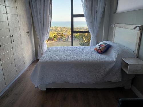 a bedroom with a bed and a large window at Kaaimans Crest Sea-View Apartments - Great Brak River in Groot Brak Rivier