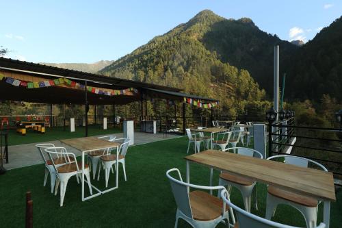 een groep tafels en stoelen met bergen op de achtergrond bij AmigosIndia Katagla in Kasol