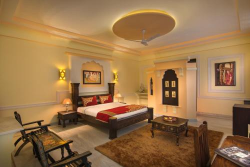 a bedroom with a bed and a living room at Syna Heritage Hotel in Khajurāho
