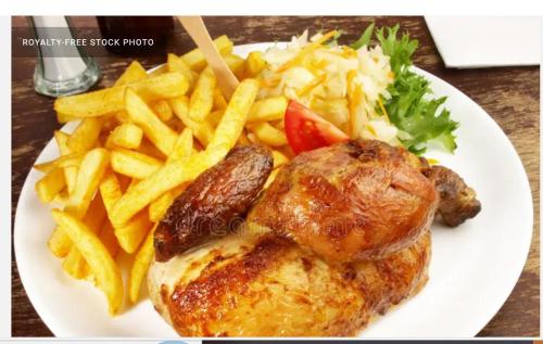 a plate of food with french fries and chicken and potatoes at Javelin Palace Hotel in Kampala