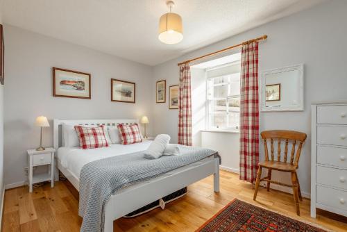 une chambre avec un lit, une chaise et une fenêtre dans l'établissement The Old Bank House - St Monans, à Saint Monance