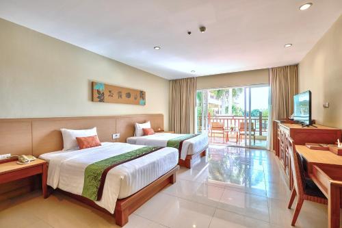 een hotelkamer met twee bedden en een televisie bij The Heritage Pattaya Beachfront Resort in Pattaya South