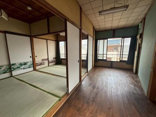 een lege kamer met houten vloeren en glazen ramen bij 桑名のお宿三栄町 in Kuwana