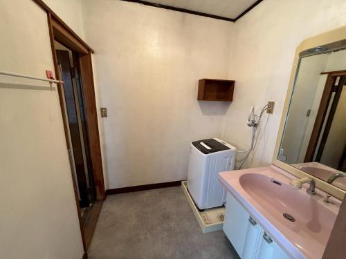 een badkamer met een roze wastafel en een spiegel bij 桑名のお宿三栄町 in Kuwana