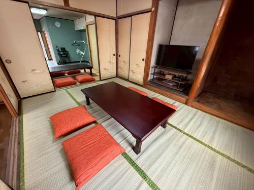 a living room with a table and a television at 桑名のお宿三栄町 桑名駅徒歩圏 ナガシマスパーランド なばなの里 近郊一軒家 in Kuwana