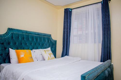 Schlafzimmer mit einem Bett mit blauem Kopfteil und einem Fenster in der Unterkunft Danross Nest in Gatunga