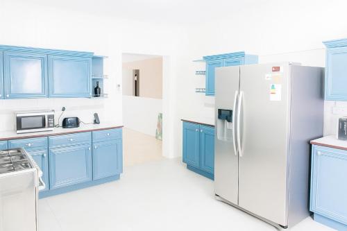 Chantal House Sleeps 8 with Garden في Buff Bay: مطبخ مع دواليب زرقاء وثلاجة