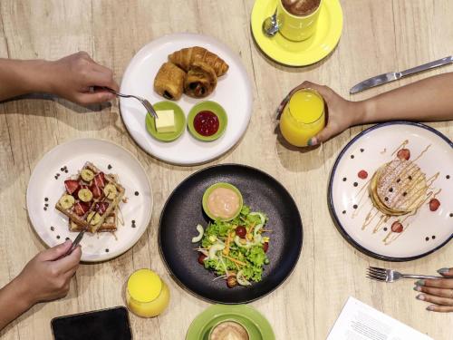 a table topped with plates of food and drinks at ibis Styles Bogor Pajajaran in Bogor