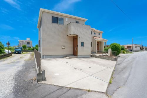 a house on a street with a driveway at Minatogawa Stay OKINAWA in Yaese