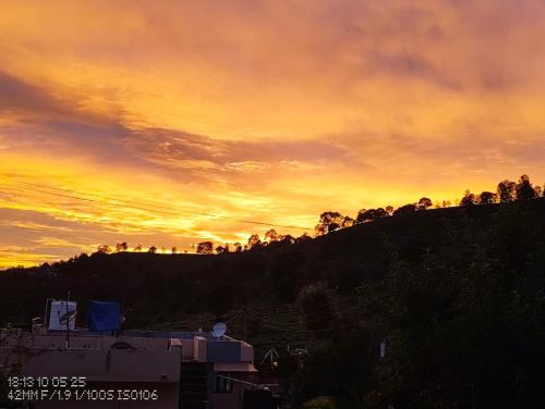 a sunset over a hill with a mountain at Pleasant Stay Coonoor-A Serene Hillside Retreat in Coonoor