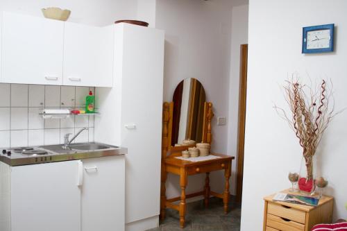 a kitchen with white cabinets and a sink and a table at Apartments "I & I" in Pag