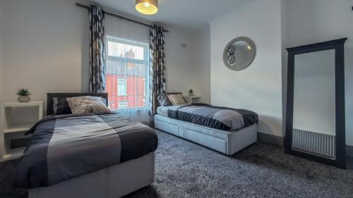 1 Schlafzimmer mit 2 Betten, einem Spiegel und einem Fenster in der Unterkunft Hexthorpe House - By Sigma Stays in Doncaster