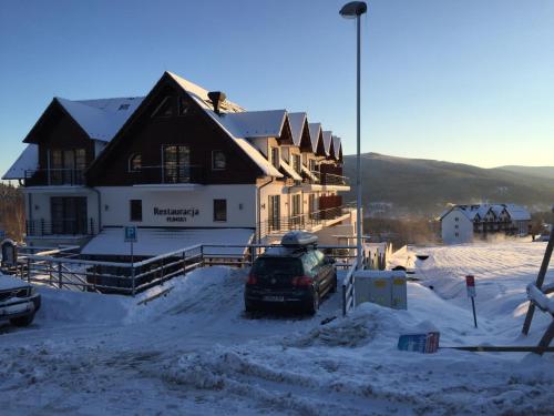 a house with a car parked in the snow at Flinski Sport X SPA, Boutique X Art in Świeradów-Zdrój