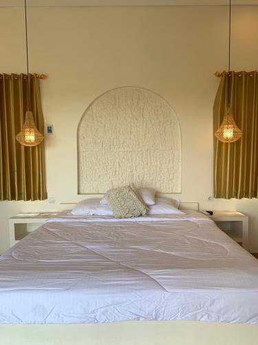 a bedroom with a large white bed with two lamps at Vikosa Villa Private Pool With View in Yogyakarta