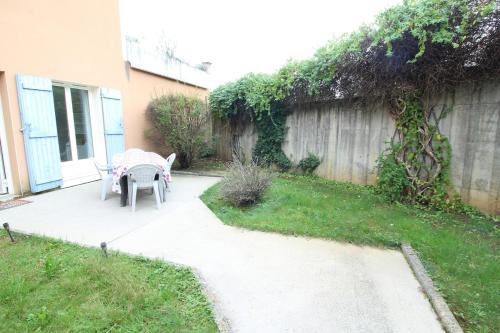 a patio with a table and chairs in a yard at Escapade Jurassienne-Terrasse & Sérénité in Lons-le-Saunier