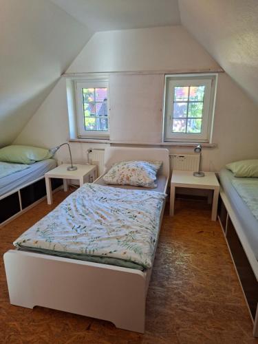 a small bedroom with two beds and two windows at Haus am Ponyhof in Aurich