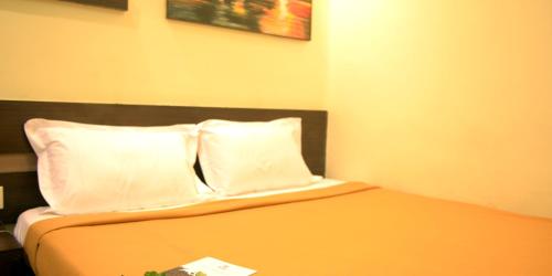 a bedroom with a bed with two pillows at Hotel Metro in Kumbakonam