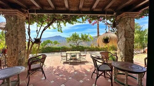 eine Terrasse mit Tischen und Stühlen und Blick auf die Berge in der Unterkunft Padre Sol Yoga Retreat Center Málaga by AndaraHolidays in Sayalonga