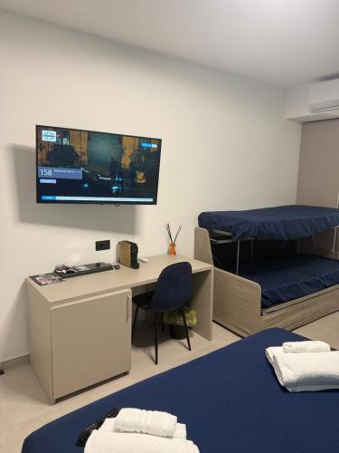 Zimmer mit einem Schreibtisch, einem Bett und einem TV in der Unterkunft Sunset Affittacamere in Cipollina