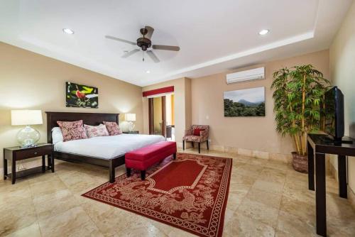 een grote slaapkamer met een bed en een rode bank bij Beachfront, Sunset, & Ocean Views With Gas Grill in Tamarindo