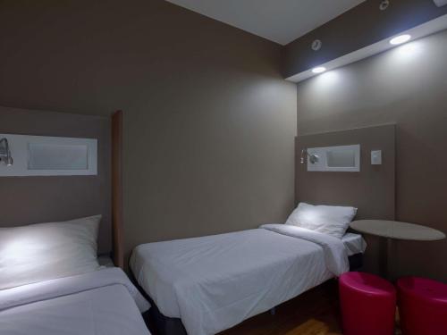 マセイオにあるibis budget Maceió Pajuçaraのベッド2台とテーブルがある小さな部屋
