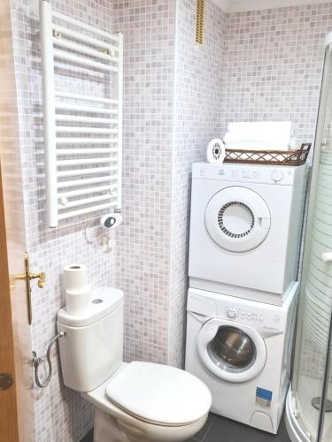 a bathroom with a toilet and a washing machine at Amanecer Camp d Aljub in Candanchú