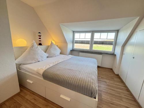 a bedroom with a large bed with a large window at Ferienwohnung Blinkfüer in Hinte