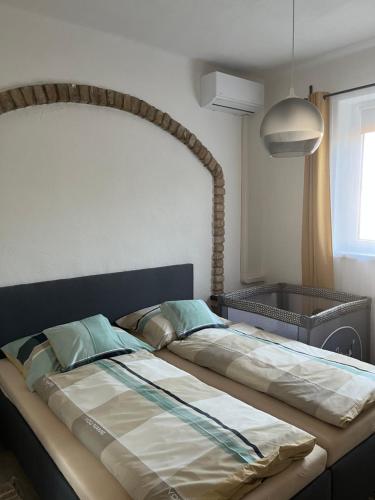 a large bed in a bedroom with a large headboard at Apartman - Garden - Vendégház 2 in Nesvady