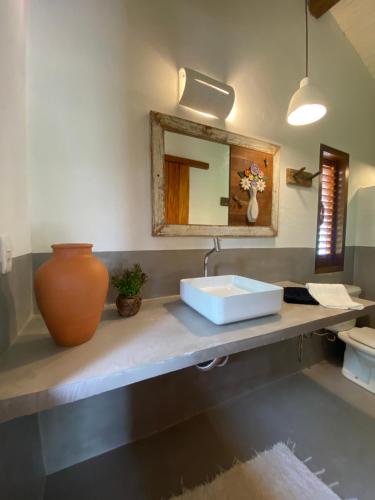 a bathroom with a sink and a vase on a counter at Pousada Porto Caraíva in Caraíva