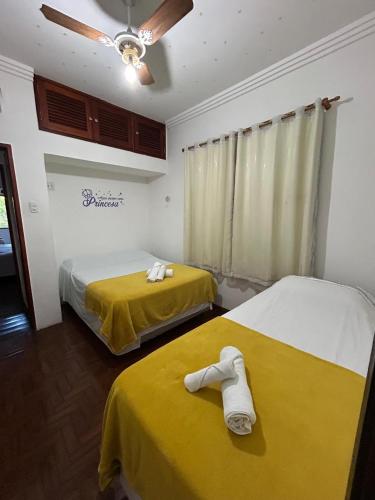 two beds in a room with yellow sheets at Casa em Penedo - Itatiaia in Itatiaia