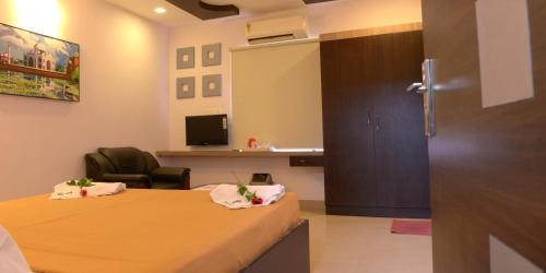 a room with two beds and a chair and a desk at Hotel Metro in Kumbakonam