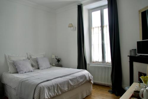 une chambre blanche avec un lit et une fenêtre dans l'établissement La Joséphine, à Cosne Cours sur Loire