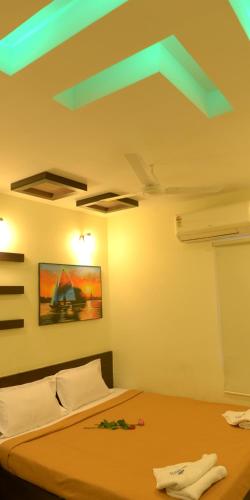 a bedroom with a bed and a ceiling with green lights at Hotel Metro in Kumbakonam