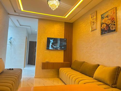a living room with a couch and a tv on a wall at Real appartement in El Jadida