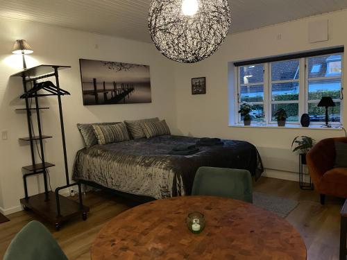 a bedroom with a bed and a table and a chandelier at Jonstrupvejens Apartments Lejl B in Ballerup