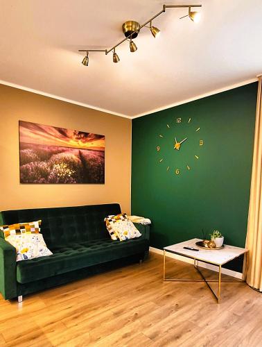 a living room with a green couch and a clock on the wall at Green Oasis House -Linini in Mārupe