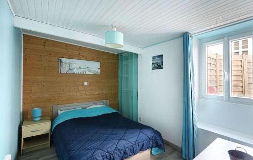 a bedroom with a blue bed and a window at La venelle des Ormeaux in Les Moulins de la Boire