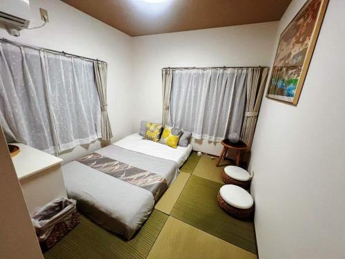 Kleines Zimmer mit 2 Betten und 2 Fenstern in der Unterkunft Ayaka House Hirai in Tokio