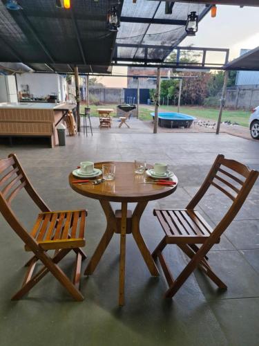 a wooden table and two chairs sitting next to a table and chairs at Suite privativo cafe hidro in Sao Jose do Rio Preto